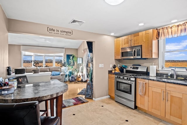 kitchen with light brown cabinets, sink, appliances with stainless steel finishes, and dark stone counters