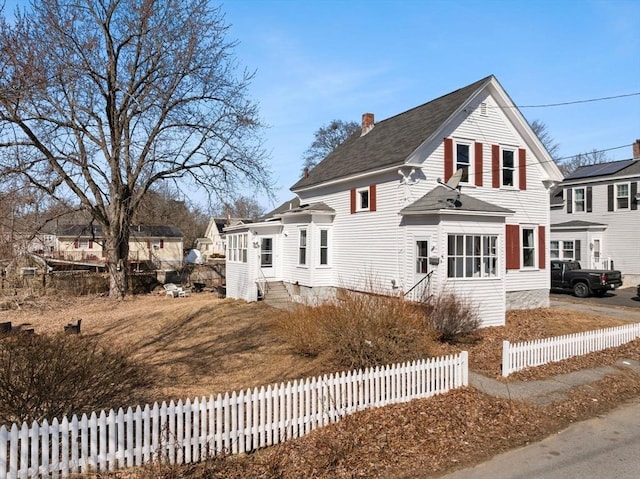 view of front of home with entry steps, a fenced front yard, and a chimney