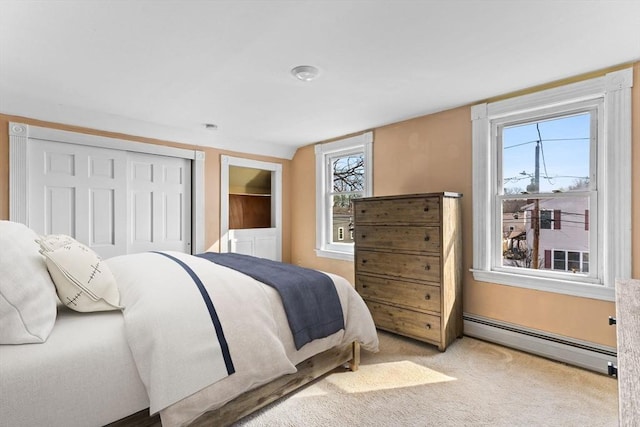 bedroom featuring a closet, baseboard heating, and carpet