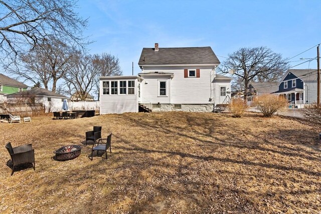 back of property with entry steps, a fire pit, fence, and a chimney