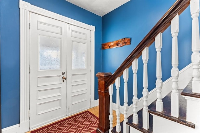 foyer with stairs, baseboards, and brick floor