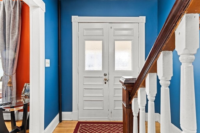 entryway featuring brick floor, stairway, and baseboards