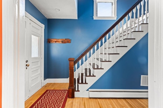 entrance foyer featuring visible vents, baseboards, stairway, hardwood / wood-style floors, and baseboard heating