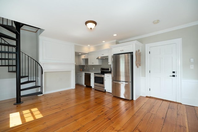 2 Court St Unit 3, Newburyport, MA 01950 - kitchen with appliances with stainless steel finishes, under cabinet range hood, white cabinets, light wood finished floors, and tasteful backsplash