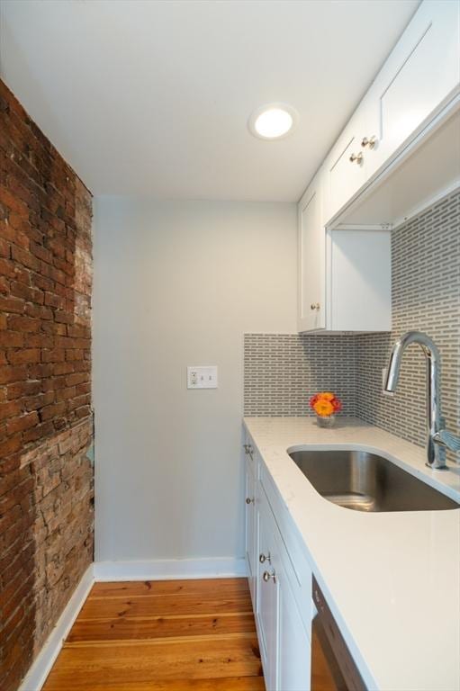 2 Court St Unit 3, Newburyport, MA 01950 - kitchen featuring light wood-type flooring, tasteful backsplash, white cabinetry, stainless steel dishwasher, and brick wall