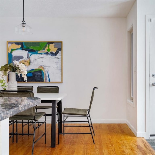 dining space with light wood finished floors and baseboards