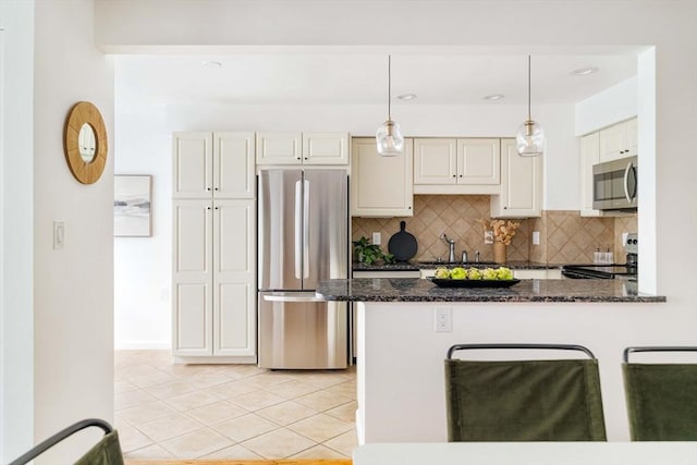 kitchen featuring stainless steel appliances, backsplash, light tile patterned floors, dark stone counters, and pendant lighting