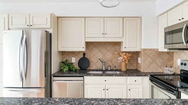 kitchen with appliances with stainless steel finishes, a sink, dark stone countertops, tasteful backsplash, and white cabinets