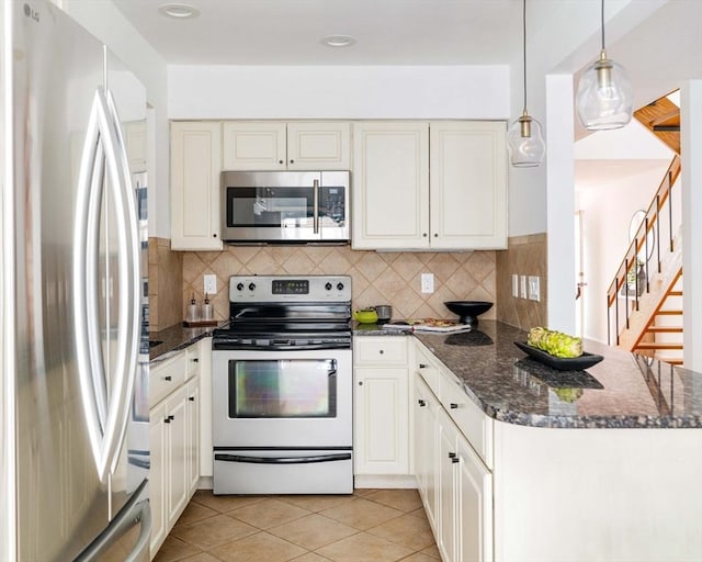 kitchen featuring stainless steel appliances, a peninsula, decorative backsplash, and dark stone counters