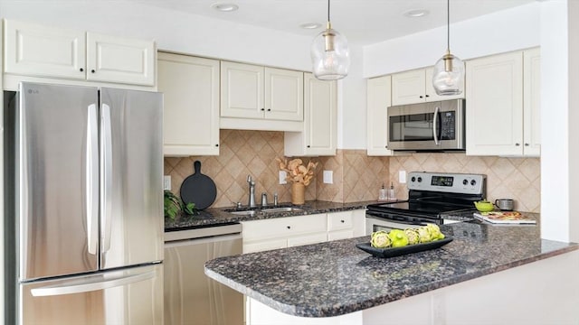 kitchen featuring appliances with stainless steel finishes, a sink, hanging light fixtures, a peninsula, and white cabinets