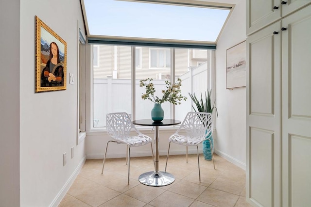 living area featuring baseboards, light tile patterned floors, and vaulted ceiling