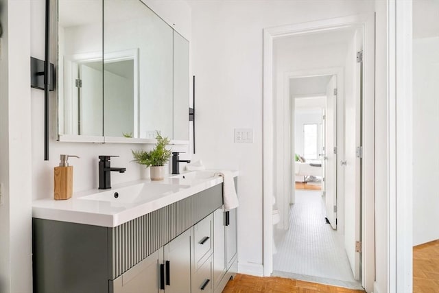 bathroom with toilet, double vanity, and baseboards