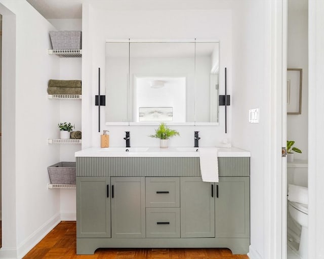 bathroom featuring toilet, double vanity, and baseboards