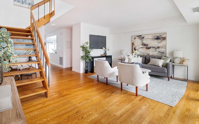 living room featuring stairs, wood finished floors, and baseboards