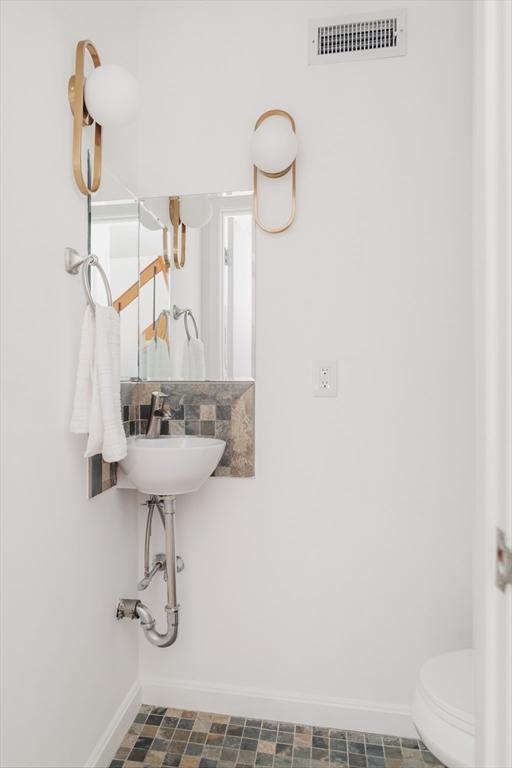 bathroom with baseboards, toilet, and a sink