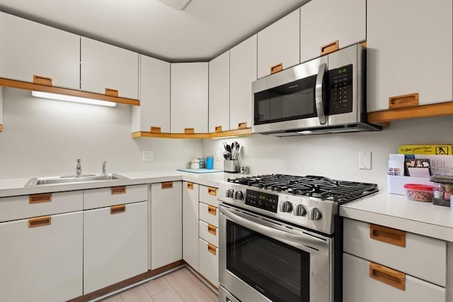 kitchen with sink, stainless steel appliances, and white cabinetry