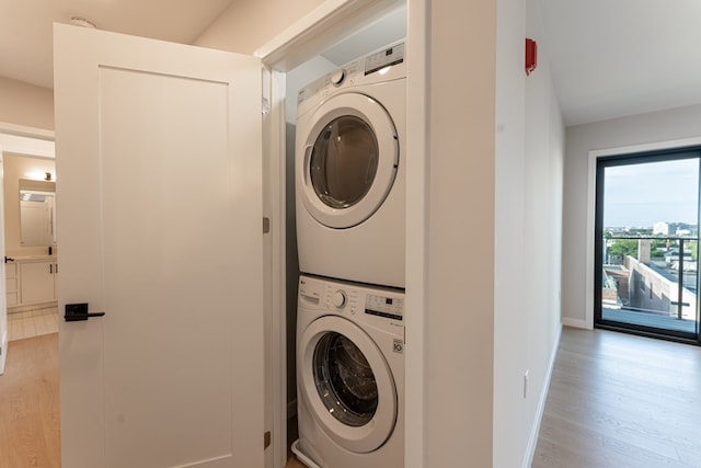 laundry room with light hardwood / wood-style flooring and stacked washer and dryer