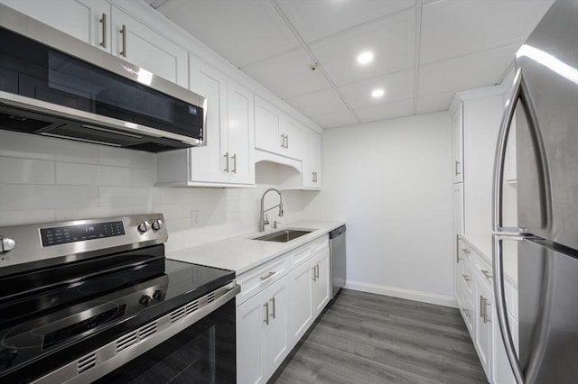 kitchen with sink, appliances with stainless steel finishes, white cabinetry, dark hardwood / wood-style floors, and tasteful backsplash