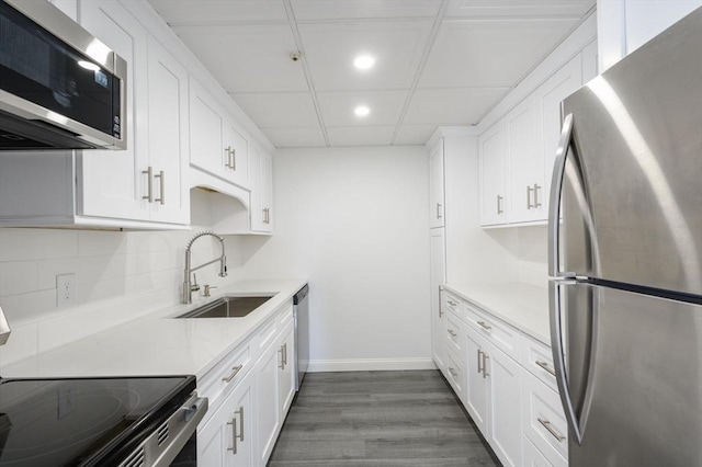 kitchen featuring appliances with stainless steel finishes, white cabinetry, sink, backsplash, and dark wood-type flooring