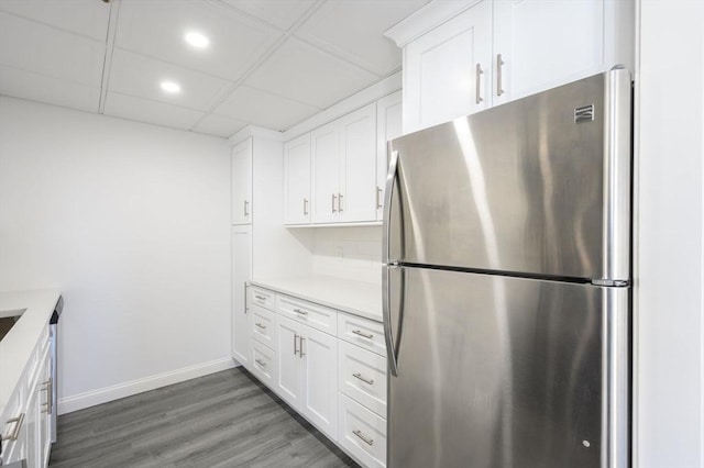 kitchen featuring white cabinets, a paneled ceiling, stainless steel fridge, and dark hardwood / wood-style flooring