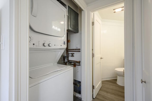 laundry room with stacked washer / drying machine and hardwood / wood-style flooring