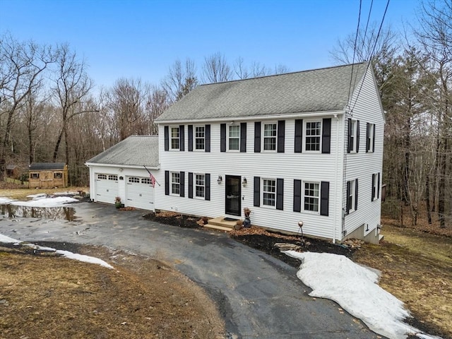 view of front of house featuring a garage, a shingled roof, and aphalt driveway