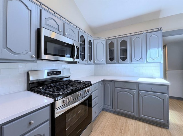 6 Oak St, Foxboro, MA 02035 - kitchen featuring stainless steel appliances, gray cabinetry, lofted ceiling, light wood-type flooring, and glass insert cabinets