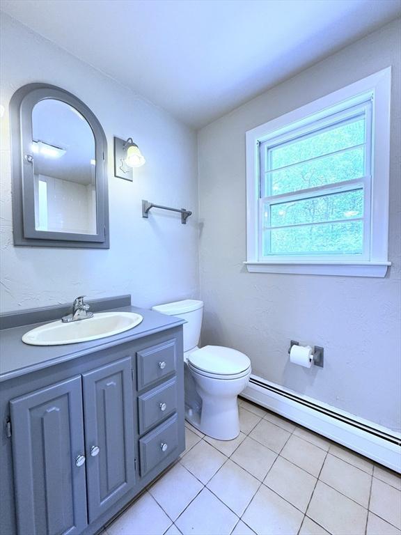 6 Oak St, Foxboro, MA 02035 - half bathroom with a baseboard heating unit, toilet, vanity, and tile patterned flooring