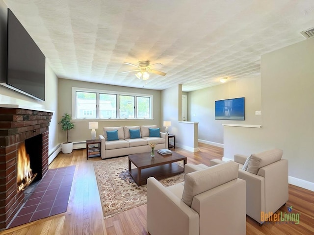 6 Oak St, Foxboro, MA 02035 - living room featuring a ceiling fan, a fireplace, a baseboard radiator, baseboards, and wood finished floors