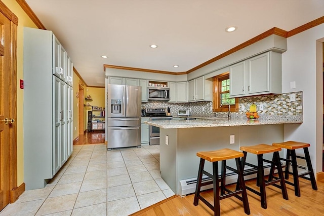 kitchen featuring decorative backsplash, appliances with stainless steel finishes, a baseboard radiator, a peninsula, and recessed lighting