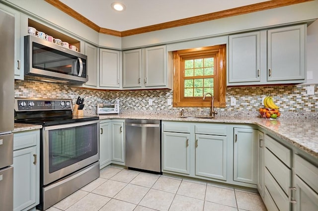 kitchen with stainless steel appliances, light tile patterned floors, ornamental molding, and a sink