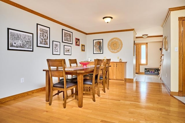 dining area featuring crown molding, baseboards, and light wood finished floors