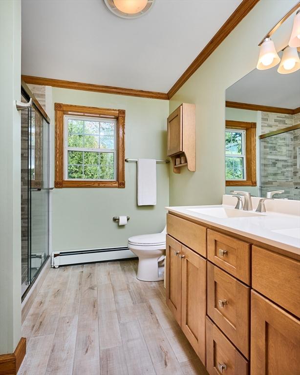 full bathroom with plenty of natural light, a baseboard heating unit, a stall shower, and wood finished floors