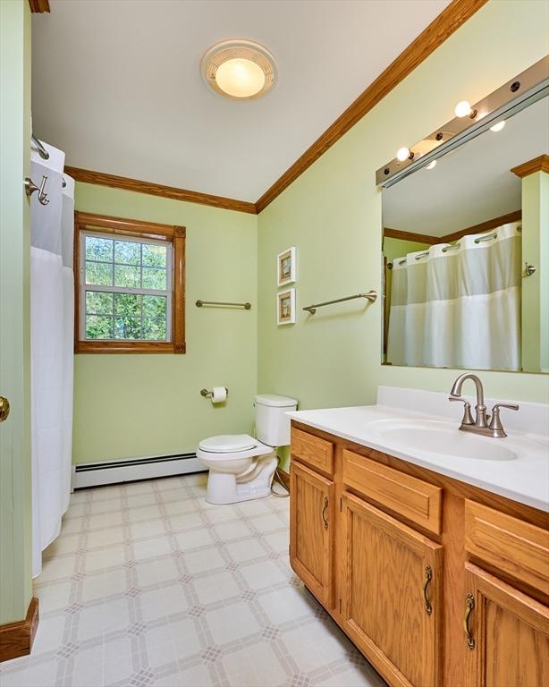 full bath featuring crown molding, vanity, toilet, baseboards, and baseboard heating