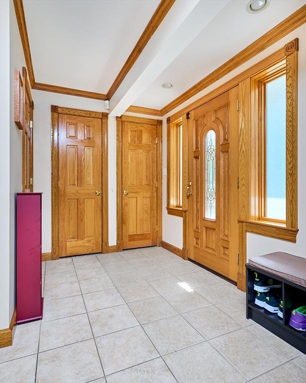 entryway featuring baseboards, ornamental molding, and light tile patterned floors
