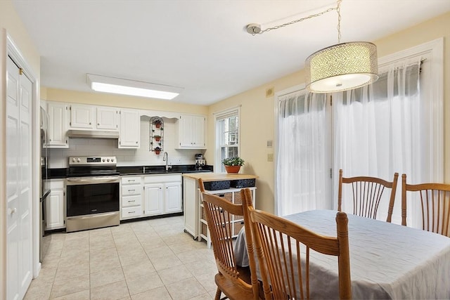 kitchen featuring under cabinet range hood, light tile patterned floors, a sink, white cabinets, and electric range