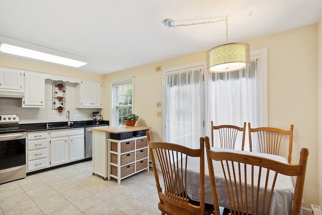 kitchen with a sink, stainless steel appliances, white cabinetry, under cabinet range hood, and decorative backsplash