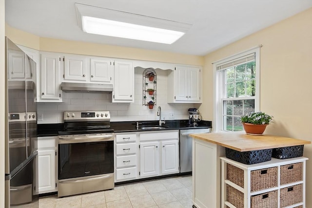 kitchen featuring a sink, under cabinet range hood, decorative backsplash, white cabinets, and appliances with stainless steel finishes