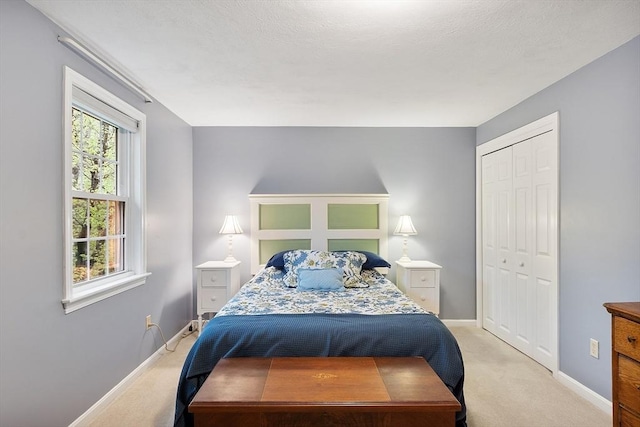 bedroom with light colored carpet, a closet, and baseboards