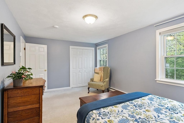 bedroom featuring light carpet, baseboards, a closet, and multiple windows