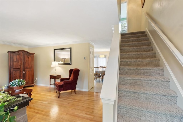 staircase featuring crown molding, baseboards, and wood finished floors