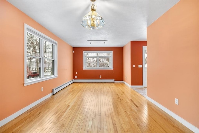 unfurnished room with light wood-type flooring, a baseboard radiator, and a chandelier