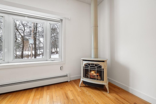 room details with hardwood / wood-style floors, a wood stove, and baseboard heating