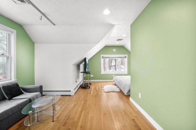 bedroom featuring light hardwood / wood-style floors, a baseboard radiator, and vaulted ceiling