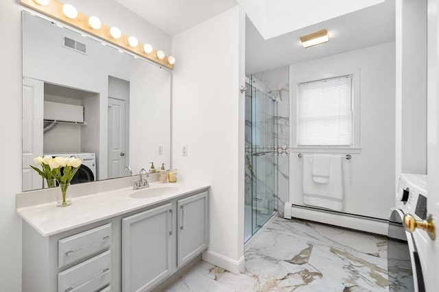 bathroom with vanity, washer / dryer, a shower with shower door, and a baseboard heating unit