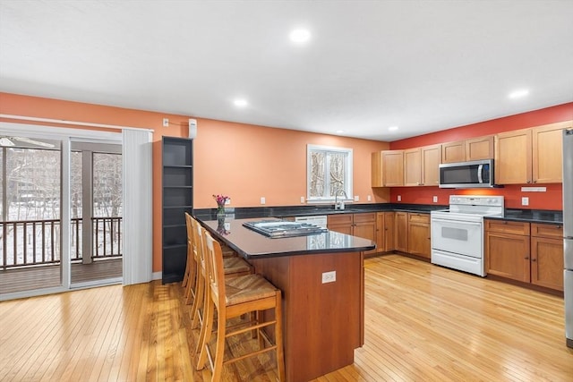 kitchen featuring a breakfast bar area, white range with electric cooktop, plenty of natural light, and light wood-type flooring