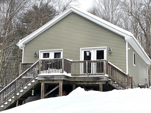 snow covered back of property featuring a deck