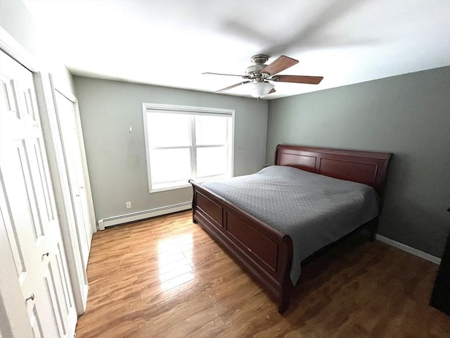 bedroom with light hardwood / wood-style flooring, ceiling fan, and baseboard heating