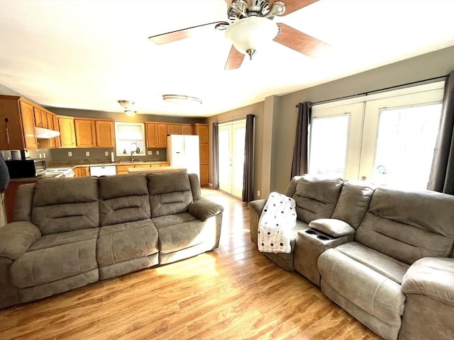 living room with light hardwood / wood-style flooring, french doors, and ceiling fan