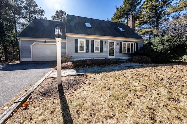 cape cod home featuring driveway and an attached garage